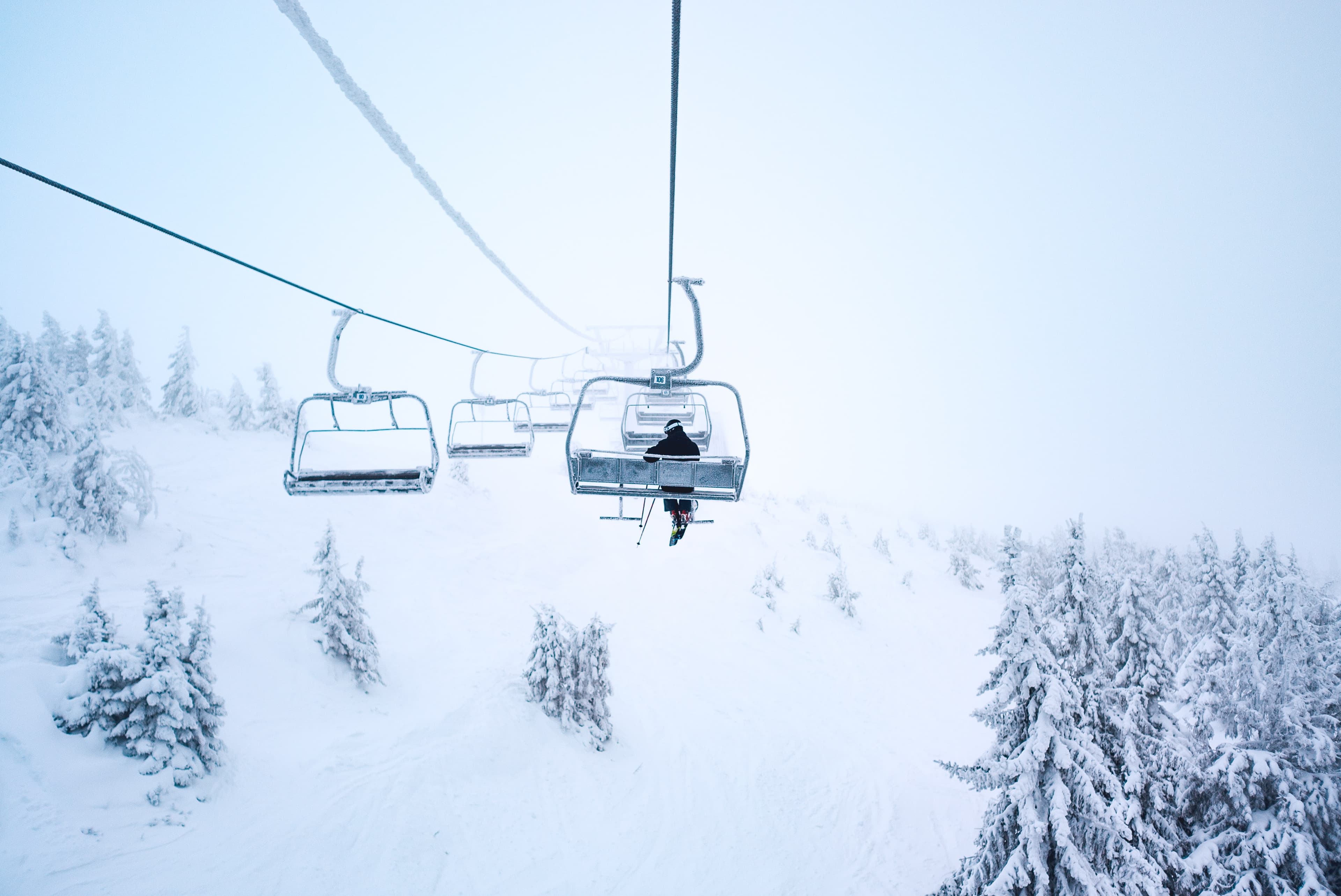 Snowy chair lift with a single skier on it